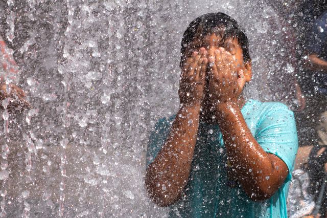 A child wipes water from his face while playing in the Changing Spaces Fountain by Jeppe Hein at Rockefeller Center during a heat wave on July 23 in New York City.
